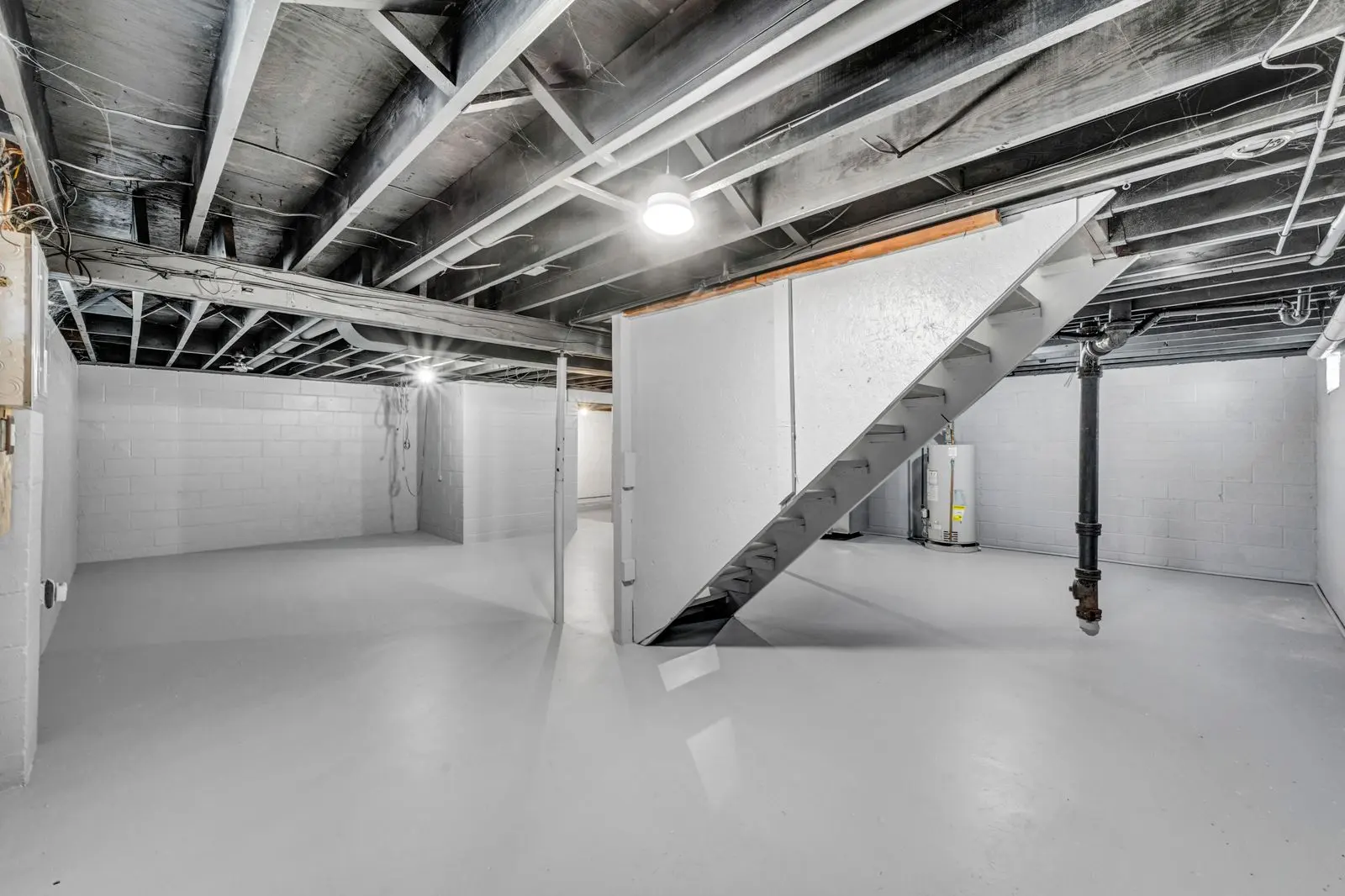 Bright unfinished basement with exposed joists and a staircase