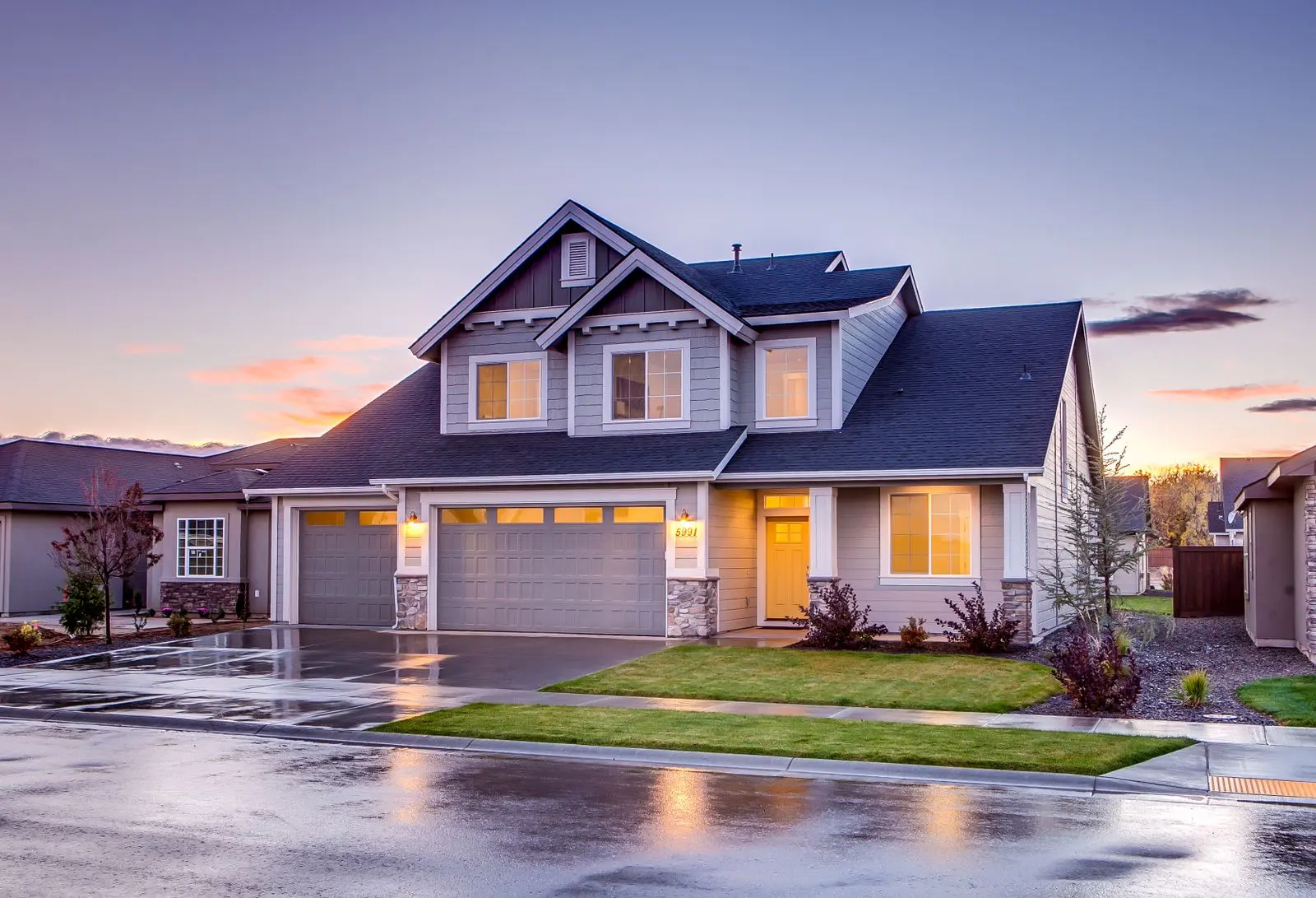 Two-story suburban home with a garage and landscaped front yard at dusk